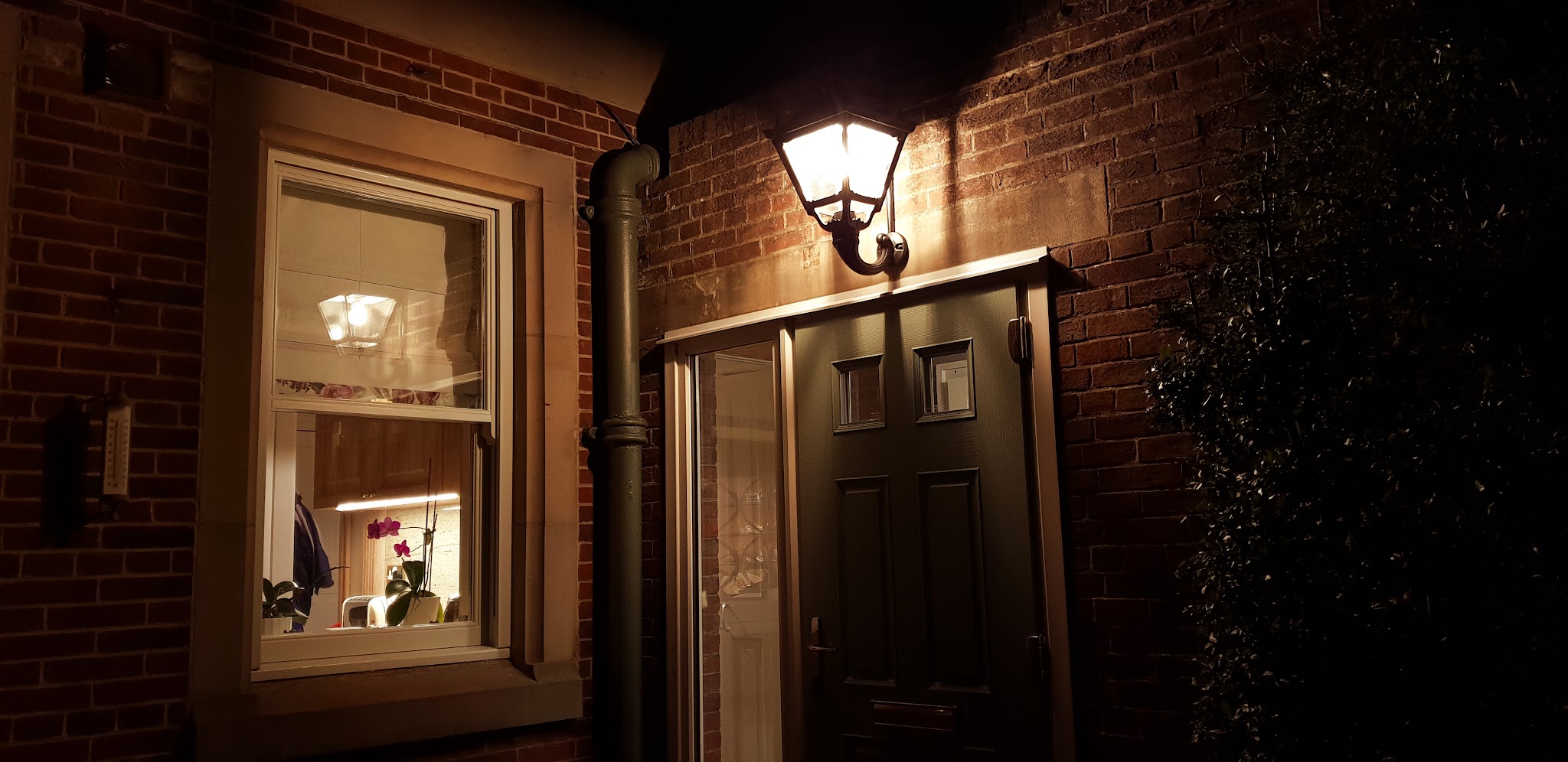 A house entrance at night lit by a wall lantern